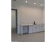 Clean, modern bar area with a sleek countertop, white cabinetry, matte black fixtures, and wood-look tile flooring at 24152 N 172Nd Ave, Surprise, AZ 85387