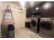 Well-lit laundry room with stainless steel washer and dryer, cabinets, and a convenient folding rack at 24228 S 211Th St, Queen Creek, AZ 85142