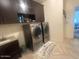 Bright laundry area with dark wood cabinets, sink, and stainless steel front loading washer and dryer at 24228 S 211Th St, Queen Creek, AZ 85142