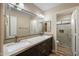 Bathroom featuring double sinks, granite countertops, dark cabinets, and a glass enclosed walk-in shower at 2449 E Desert Flower Ln, Phoenix, AZ 85048