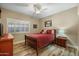 Cozy bedroom with a full-sized bed, wood floors, neutral walls, window shutters, and a ceiling fan at 2449 E Desert Flower Ln, Phoenix, AZ 85048