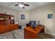 Spacious home office with wood floors, a dark ceiling fan, two desks, and built-in storage at 2449 E Desert Flower Ln, Phoenix, AZ 85048