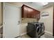 Laundry room featuring a front-load washer and dryer, wood-look floors, and upper cabinets at 2449 E Desert Flower Ln, Phoenix, AZ 85048
