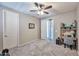 Neutral bedroom with a ceiling fan and a desk area and adjacent room through an open door at 2468 W Dapple Gray Ct, San Tan Valley, AZ 85144