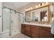 Bathroom featuring double sinks with granite counters and large walk-in shower with glass door at 29624 N 128Th Ln, Peoria, AZ 85383