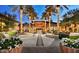 Beautifully lit exterior view of a building with palm trees, outdoor seating, and lush landscaping at dusk at 29624 N 128Th Ln, Peoria, AZ 85383