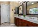 This bathroom offers a double sink vanity with dark wood cabinets and framed mirrors at 3150 E Isaiah Ave, Gilbert, AZ 85298