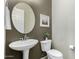Charming powder room with pedestal sink, round mirror, neutral walls and contemporary fixtures at 3150 E Isaiah Ave, Gilbert, AZ 85298
