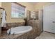 This bathroom showcases a drop-in tub and walk-in shower with tan tiling at 3150 E Isaiah Ave, Gilbert, AZ 85298