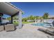 Covered patio with wicker furniture overlooks the pool and lush backyard, perfect for relaxation at 3252 E Lexington Ave, Gilbert, AZ 85234
