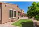 Charming backyard showcasing a covered patio, lush artificial turf, paved area, and a planter with colorful flowers at 3269 E Ironside Ln, Gilbert, AZ 85298