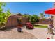 Relaxing backyard area with pavers, seating, a red umbrella, potted flowers, and a well-kept perimeter fence at 3269 E Ironside Ln, Gilbert, AZ 85298