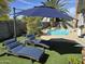 Backyard lounge area with sun umbrella, overlooking inviting pool and water feature at 4061 W Tonopah Dr, Glendale, AZ 85308