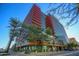 A modern, multi-story building with red accents and palm trees, set against a bright blue sky at 4808 N 24Th St # 527, Phoenix, AZ 85016