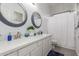 Bathroom with dual sinks, white cabinets, granite countertops, and decorative round mirrors at 5639 S Four Peaks Pl, Chandler, AZ 85249