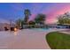 Backyard with a pool, spa, lounge chairs, fire pit, and manicured landscaping at twilight at 5639 S Four Peaks Pl, Chandler, AZ 85249