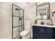 Updated bathroom featuring a glass enclosed shower, chevron wall tile, and a navy blue vanity at 7869 W Market St, Glendale, AZ 85303