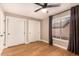 Bedroom with ceiling fan, window, warm wood flooring, grey curtains, and closet space at 7869 W Market St, Glendale, AZ 85303