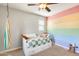 This bedroom has a colorful accent wall, ceiling fan, daybed with storage, and natural light at 890 W Zion Pl, Chandler, AZ 85248