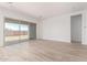 Bright living room featuring wood-look tile flooring, neutral paint, and a large sliding glass door at 11660 W Luxton Ln, Avondale, AZ 85323