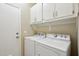 Functional laundry room with white washer and dryer, and upper cabinets at 12425 W Jefferson St, Avondale, AZ 85323
