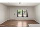 A freshly painted empty living room showcasing new flooring, a door, and a large window at 1424 S Bonarden Ln, Tempe, AZ 85281