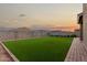 The backyard features an artificial turf lawn, brick-lined edges, and a concrete fence, offering a serene outdoor space at 17813 W Pinnacle Vista Dr, Surprise, AZ 85387