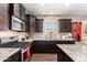 Beautiful kitchen with stainless appliances, granite countertops, dark cabinets, and wood-look tile flooring at 19887 N Herbert Ave, Maricopa, AZ 85138
