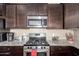 This kitchen features stainless steel appliances, granite counters, and dark wood cabinets at 19887 N Herbert Ave, Maricopa, AZ 85138