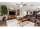 Open-concept living room featuring a sectional sofa, ceiling fan, and wood-look tile flooring at 19887 N Herbert Ave, Maricopa, AZ 85138