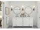 Bathroom with white cabinets, dual sinks, circular mirrors and modern lighting fixtures at 20309 W Roma Ave, Buckeye, AZ 85396