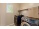 Functional laundry room featuring modern washer and dryer units and a storage shelf above at 20733 W Alsap Rd, Buckeye, AZ 85396