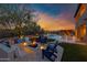 Inviting backyard with a fire pit, lounge chairs, pool, and lush landscaping at dusk at 30129 N 52Nd Pl, Cave Creek, AZ 85331