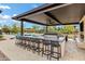 A well-equipped outdoor kitchen featuring a long countertop with bar stools and a built-in grill, ideal for outdoor dining at 30129 N 52Nd Pl, Cave Creek, AZ 85331