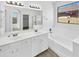 Bright bathroom featuring double sinks, soaking tub, and a large mirror providing natural light at 3013 S 102Nd Ln, Tolleson, AZ 85353