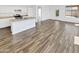 Open-concept kitchen and living area with wood-look tile, white cabinets, and stainless steel appliances at 3013 S 102Nd Ln, Tolleson, AZ 85353