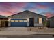 Charming single-story home featuring a blue garage door and desert landscaping at sunset at 37126 W Prado St, Maricopa, AZ 85138