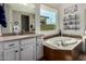 Bright bathroom featuring a soaking tub, granite counters, vanity, and a large window at 3751 E Zachary Dr, Phoenix, AZ 85050