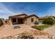 Home's backyard featuring brick patio, small lawn, and desert landscaping at 42311 W Bunker Dr, Maricopa, AZ 85138