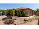 Well-maintained front yard with desert landscaping, including rocks and small trees at 42311 W Bunker Dr, Maricopa, AZ 85138