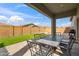 Covered patio with an outdoor dining table, brick pavers, synthetic grass, and perimeter block fencing at 460 W Glacier Bay Dr, San Tan Valley, AZ 85140