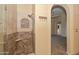 Tiled walk-in shower with built-in seat, towel hooks, and arched doorway to main bedroom at 5226 W Pontiac Dr, Glendale, AZ 85308
