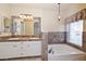 Bathroom features a soaking tub, double sink vanity with decorative mirror and window at 5226 W Pontiac Dr, Glendale, AZ 85308