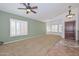 Inviting living room featuring carpeted floors, high ceilings, ceiling fan, natural light, and wood paneled wall at 5226 W Pontiac Dr, Glendale, AZ 85308