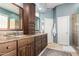 Bathroom featuring dual sinks, granite countertop, wooden cabinetry, and walk-in shower at 6094 E Evening Glow Dr, Scottsdale, AZ 85266