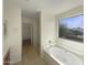 Relaxing primary bathroom with soaking tub, wood-look floors, and bright natural light creating a spa-like feel at 6602 S 23Rd Ave, Phoenix, AZ 85041