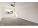 A sunny bedroom with a ceiling fan, plush carpet, and a window view at 6823 W Coolidge St, Phoenix, AZ 85033