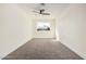 A bright bedroom with a large window, ceiling fan, and plush carpet at 6823 W Coolidge St, Phoenix, AZ 85033