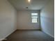 An empty, neutral carpeted bedroom illuminated by a window and a ceiling light at 9543 W Parkway Dr, Tolleson, AZ 85353