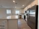 An open kitchen offers stainless steel appliances, white cabinets, an island, and hardwood floors at 9543 W Parkway Dr, Tolleson, AZ 85353